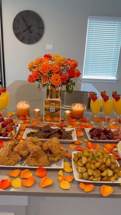 an assortment of food on a table with candles and flowers in vases next to it