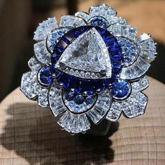 "Specification:- *Diamond Material : Cubic Zirconia *Center Diamond Cut : Trillion Cut *Center Diamond Dimension : 9.40 MM *Side Diamond Dimension : 1.10, 1.20,1.40, 3.00 MM *Side Diamond Weight : 0.89 CT *Diamond Color : White, Blue *Diamond Clarity : VVS *Making Process: Handmade by our Experienced Staff. *Stamp: Our All Rings Stamped According to metal Purity (925 SIL/10K/14K/18K). Custom Order:- *We do Accept Custom order. *Buyer can also request customization in listed Items (Charges apply White Sapphire Ring With Center Stone For Wedding, Luxury Sapphire Cluster Ring For Wedding, Luxury Cubic Zirconia Flower Ring For Wedding, Luxury Cluster Sapphire Wedding Ring, White Sapphire Ring With Halo Setting For Wedding, Fine Jewelry Sapphire Ring For Party, Luxury White Sapphire Ring With Cubic Zirconia, White Sapphire Wedding Ring In Fine Jewelry Style, White Sapphire Wedding Ring Fine Jewelry