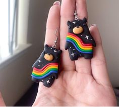 a hand holding two small black bears with rainbows and stars on it's ear