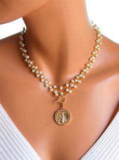 "This a a beautiful triple layer pearl necklace with a large Mary pendant hanging from toggle front. These lovely layers are made of 6mm freshwater pearls on 24k gold-plated brass with a 18k gold filled Mother Mary pendant, measuring 25mm, hanging form the gold filled toggle. This necklace can be worn many ways as shown in photos. Comes in a 50\" length. All my jewelry comes in a cute gift box with jewelry care instructions. If you would like this style necklace made with a gemstone, please send Cheap Gold Necklaces With Large Beads, Gold Double Strand Pearl Necklace, Gold Double Strand Pearl Necklace For Jewelry Making, Gold Multi-strand Pearl Charm Necklace, Gigi 2023, Pearl And Gold Necklace, Necklace Women Gold, Baroque Necklace, 14kt Gold Jewelry