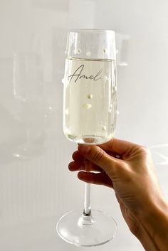 a hand holding up a wine glass with an inscription on it