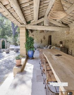 an outdoor dining area with wooden table and chairs, potted plants on the side