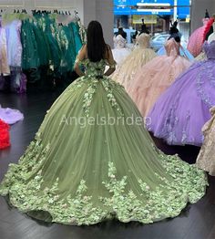 a woman looking at dresses on display in a clothing store with other gowns behind her