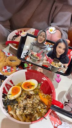 two women taking pictures of food on their cell phones while they sit at a table