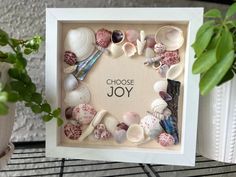 there is a frame with shells in it and the words choose joy written on it