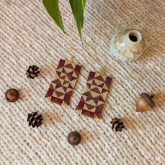 the beaded earrings are next to pine cones and shells