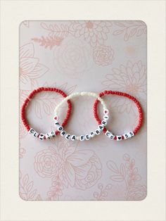 three red and white beaded bracelets with the word love written on them in small letters