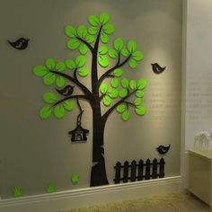 a tree with green leaves and birds painted on the wall next to a white fence