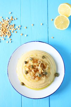 a bowl of hummus with seeds and lemons next to it on a blue table