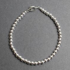 This classic sterling silver bead bracelet is beautiful and eye catching.  This is a single strand bracelet strung with 4mm seamless sterling silver round beads.  This bracelet is completely handmade by myself in my studio.  All components including the clasp are sterling silver.  It is strung using a flexible bead wire to ensure it will last for a very long time.  It will arrive in a pretty kraft gift box.  This silver bracelet is a treasure!  It would make a lovely gift!Choose your preferred l Classic Sterling Silver Beaded Bracelet For Gifts, Classic Sterling Silver Bracelet With Round Beads For Gifts, Classic Sterling Silver Beaded Bracelets With Spacer Beads, Classic Sterling Silver Bracelets With Spacer Beads, Classic Sterling Silver Beaded Bracelets With Polished Beads, Classic Sterling Silver Bracelet With Polished Beads As Gift, Classic Sterling Silver Polished Beads Bracelet, Classic Silver Beaded Bracelet Single Strand, Classic Silver Single Strand Beaded Bracelets