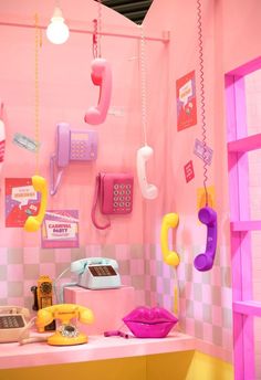 a room with pink walls and various telephones on the wall, including two phones