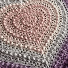 a crocheted blanket is shown with pink and white circles in the center, on a purple background