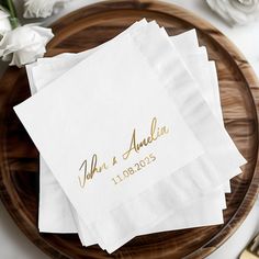 three personalized napkins on top of a wooden platter with flowers and forks