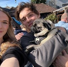 a man and woman are holding a small pug