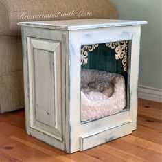 a small dog bed in an old wooden crate on the floor next to a couch