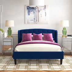 a bed with purple and white pillows in a bedroom next to a painting on the wall