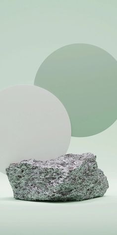 three round objects sitting on top of a rock in front of a light green background