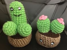 two crocheted cactus sitting next to each other on top of a black table