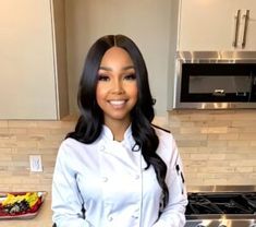 a woman standing in front of a kitchen counter with food on the counter and an oven behind her