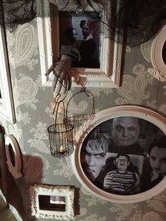 two framed pictures hang on the wall next to an old fashioned mirror and birdcage