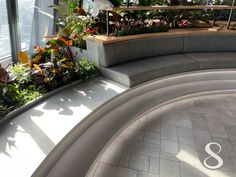 a curved bench with plants in the middle of it and a window behind it that overlooks a cityscape