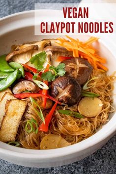 a white bowl filled with noodles and veggies on top of a gray table