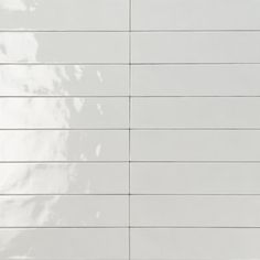 a white tiled wall with vertical lines on the bottom and one line at the top