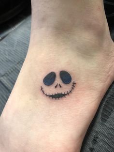 a small tattoo on the foot of a person with a jack - o'lantern face