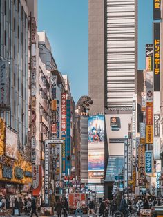 a busy city street filled with lots of tall buildings and people walking on the sidewalk