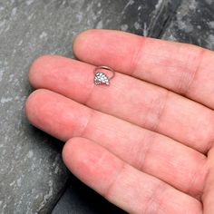 a hand holding a tiny diamond ring on it's palm