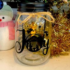 a glass jar sitting on top of a table next to a snowman and christmas tree