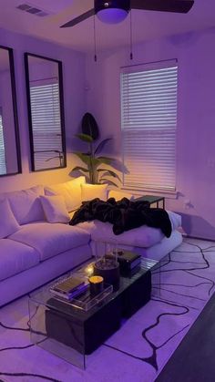 a living room filled with white furniture and purple lighting on the walls, along with two large windows