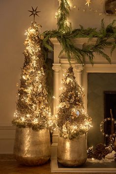 two gold pots with christmas trees in them sitting on a table next to a fireplace