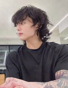 a young man sitting at a table with food in front of him and looking off into the distance