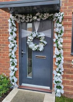 a front door decorated with flowers and greenery