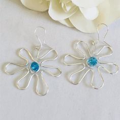 These boho style earrings are made by shaping a heavy gauge silver tone wire into the shape of a plumeria flower! The flower is accented with a turquoise crystal bead that has been wire wrapped around the center. Choose sterling silver or silver plated ear wires from the drop down menu.  Matching necklace is also available here:  https://www.etsy.com/listing/996818180/wire-flower-necklace-boho-necklace?click_key=6d1fa0166160b9a4fccf122d16c44bf61070da65%3A996818180&click_sum=9d13cef3&ref=shop_hom Silver Flower-shaped Metal Earrings, Bohemian Silver Flower Shaped Earrings, Silver Flower-shaped Metal Hoop Earrings, Bohemian Silver Flower-shaped Earrings, Silver Bohemian Flower-shaped Earrings, Silver Metal Flower Hoop Earrings, Bohemian Sterling Silver Flower Earrings With Ear Wire, Unique Silver Flower Earrings For Pierced Ears, Handmade Metal Flower Shaped Earrings