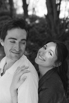 black and white photograph of a man and woman smiling at the camera with trees in the background