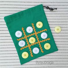 a green bag with buttons on it sitting next to a pair of scissors and thread