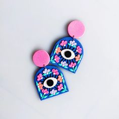 two blue and pink earrings with eyeballs on top of each earring, both decorated with flowers