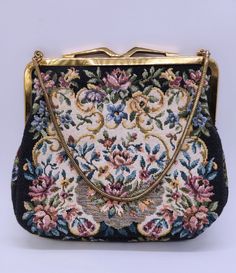 "Embrace the allure of this vintage 1940s Tapestry Purse, a delightful piece with a touch of history. Inside, you'll find a tag that proudly states \"Made in West Germany\" and \"Sanger Harris, Dallas,\" adding to its unique charm and provenance. With a black background adorned with vibrant tapestry flowers, this purse exudes timeless elegance and retro glamour. Measuring 6\" wide, 5.5\" deep, and 1\" thick, it combines style and practicality seamlessly. The chain provides a 5\" drop to the purs Vintage Tapestry Bag For Evening, Vintage Tapestry Shoulder Bag With Detachable Strap, Tapestry Purse, Vintage Tapestry Bag With Detachable Handle, Vintage Tapestry Bag With Adjustable Strap, Antique Tapestry Evening Bag, Retro Glamour, Vintage Tapestry, Top Handle Bags