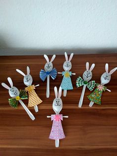 paper rabbits are sitting in the middle of a table with their names on them, and one is wearing a dress