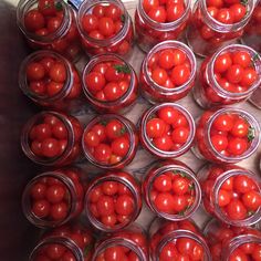 many jars filled with tomatoes sitting on top of a table