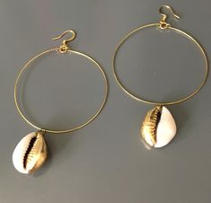 The cowrie shell once utilized as exchange currency, is revered as a symbol of fertility, goddess protection, wealth, and powerful in its connection to the strength of the ocean.  These shells have been hand leafed with gold tone leaf, base metal hoops and ear wires.  Few pairs available as these are custom made to order. Gold Small Hoop Jewelry For The Beach, Spiritual Gold Shell-shaped Jewelry, Gold Hoop Jewelry For Beach, Spiritual Gold Shell Jewelry, Gold Pierced Hoop Earrings For Beach, Gold Small Hoop Earrings For The Beach, Handmade Gold Hoop Earrings For Beach, Handmade Gold Dangle Shell, Gold Metal Hoop Earrings For Beach