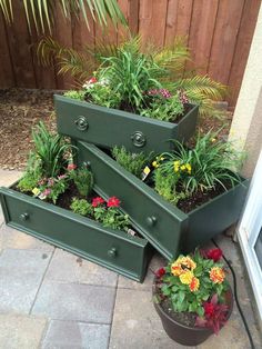 three green planters filled with different types of flowers