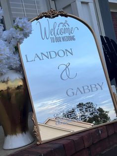 a large mirror sitting on top of a brick wall next to a vase filled with flowers