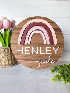 a wooden sign that says henley fade with a rainbow in the center and flowers behind it