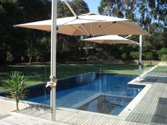 an outdoor pool with umbrellas on the side and grass in the backround