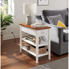 a living room with a couch, coffee table and lamp on the end table in front of it