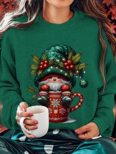 a woman wearing a green christmas sweater holding a coffee mug with santa clause on it