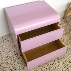 a pink dresser sitting on top of a floor next to a wall